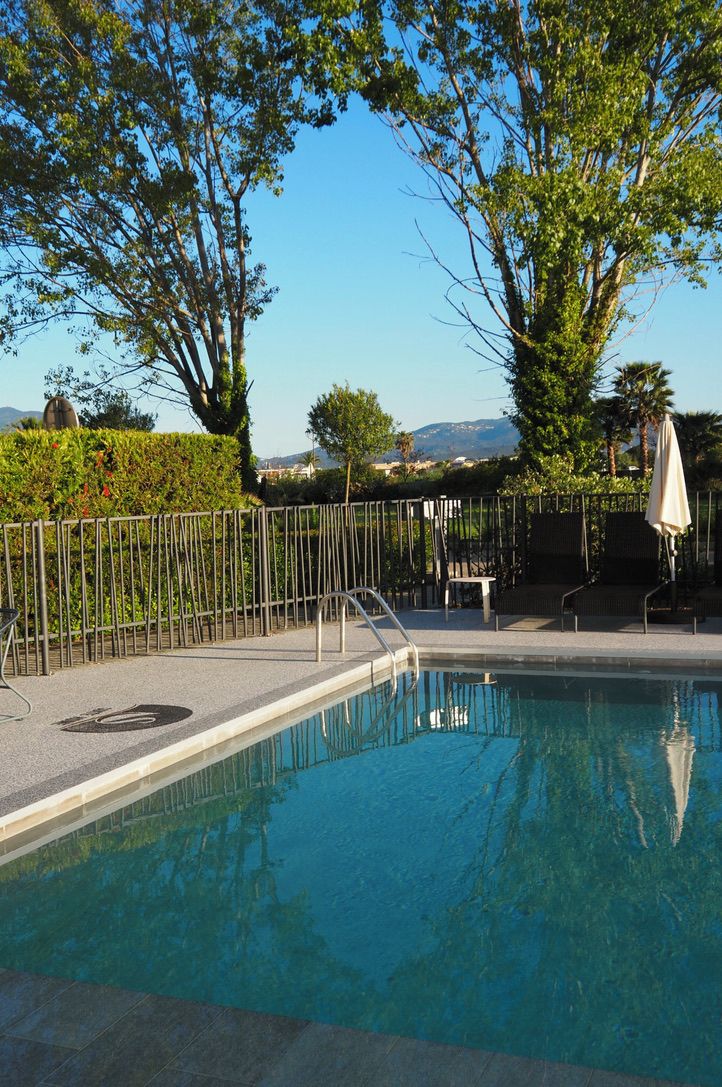 Piscina limpia con una cerca metálica, sillas de descanso y vistas a montañas distantes.