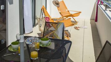 Varanda com mesa posta para o café da manhã, incluindo croissants, suco e uma xícara de café.