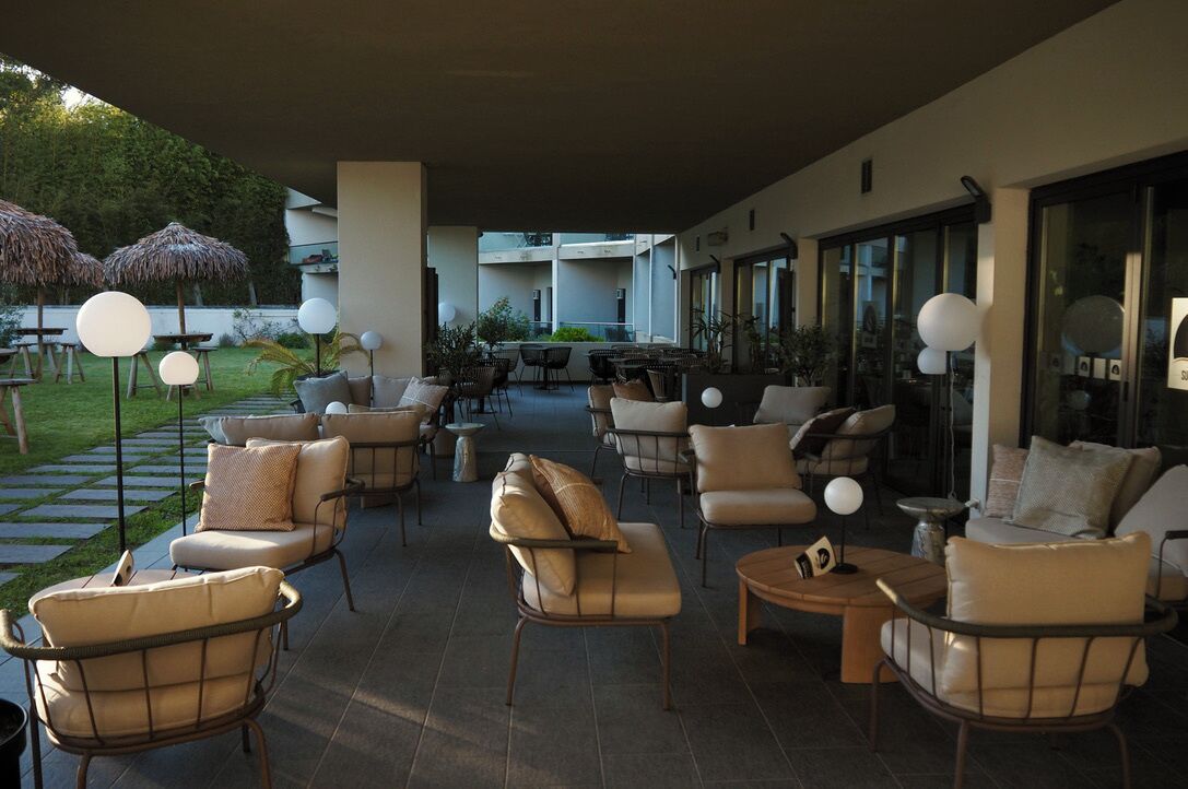 An outdoor lounge area with multiple seating arrangements, including sofas and chairs, and a few umbrellas.