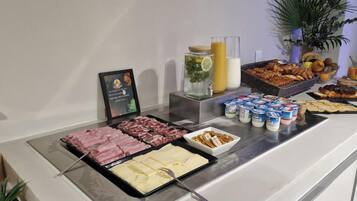 A buffet with various food items including meats, cheeses, and pastries.
