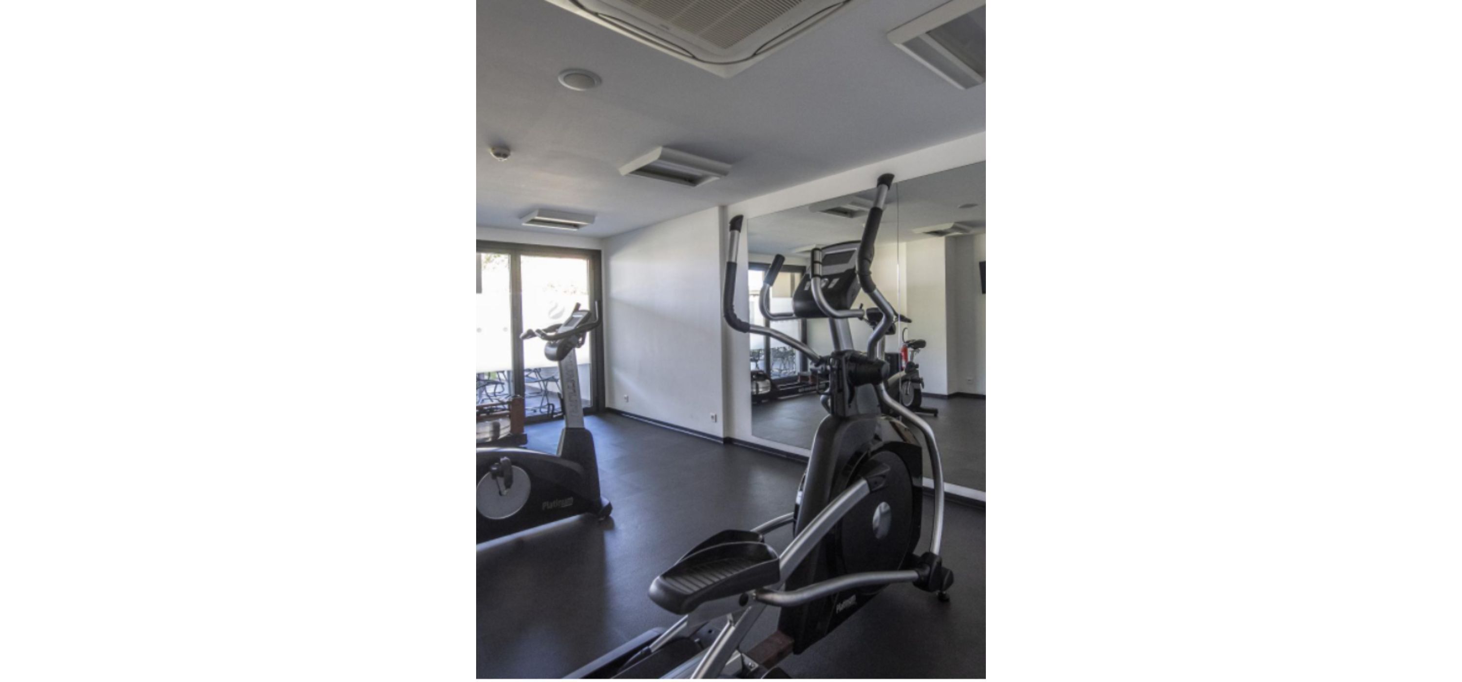 Un gimnasio con bicicletas estáticas y una caminadora.