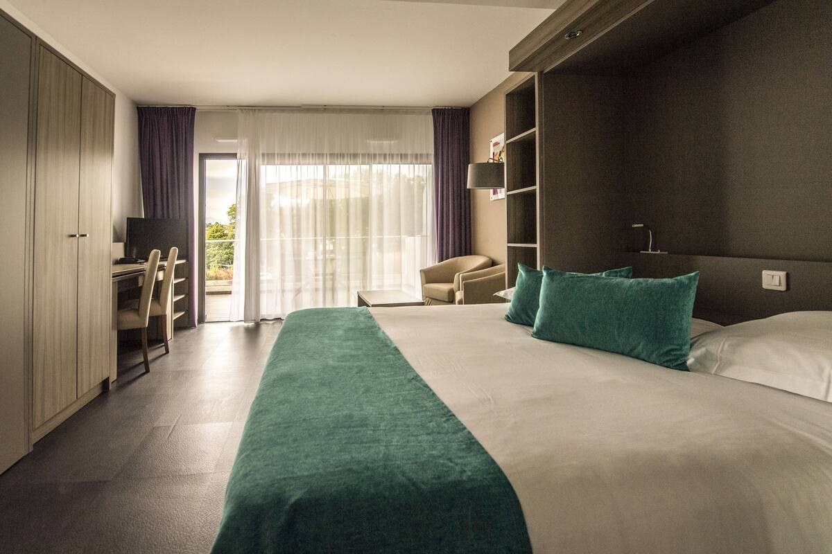 Ein Hotelzimmer mit einem großen Bett, einem Schreibtisch und einem Sessel.