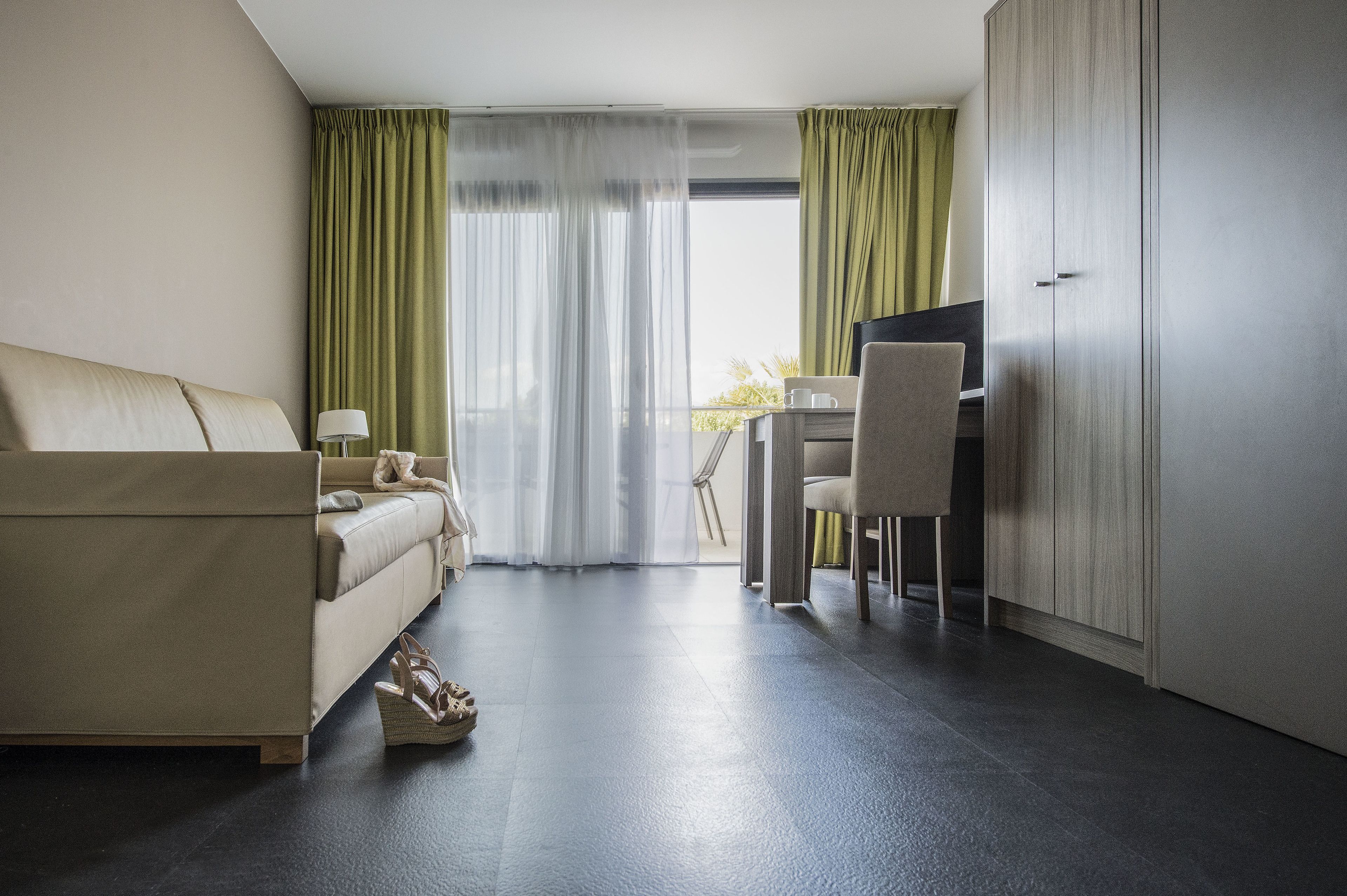 Una habitación de hotel moderna con sofá, escritorio y armario.