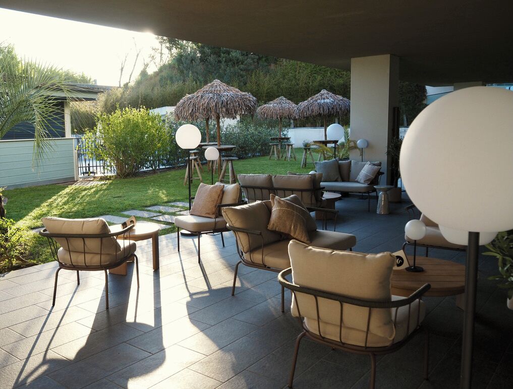 Un espacio de patio al aire libre con un conjunto de sofás y sillas, rodeado de sombrillas y una pequeña mesa.