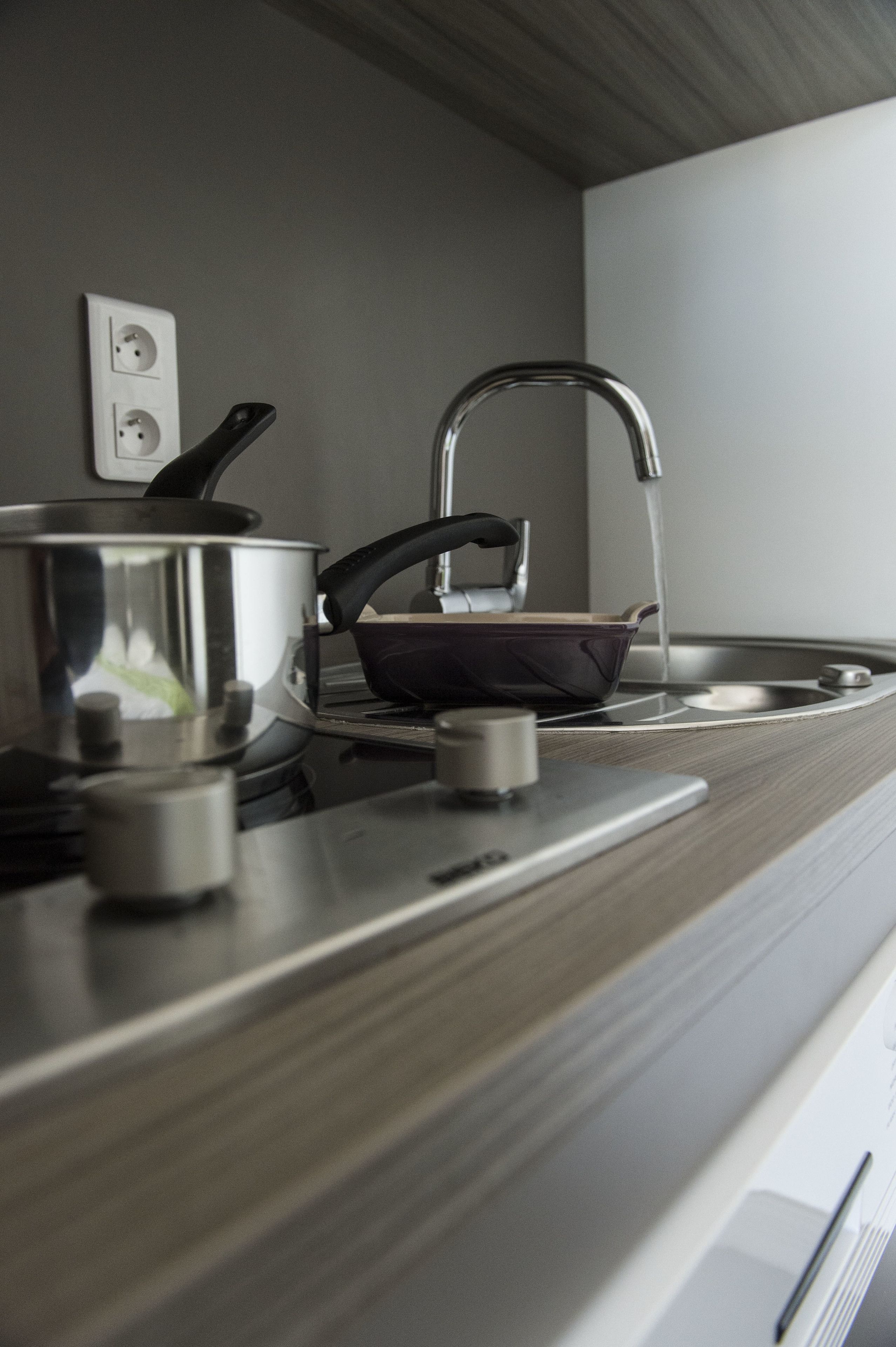 Una cocina con estufa, una olla y una sartén sobre la encimera.