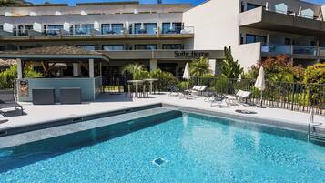 A hotel with a swimming pool, outdoor seating, and a 'Suite Home' sign.