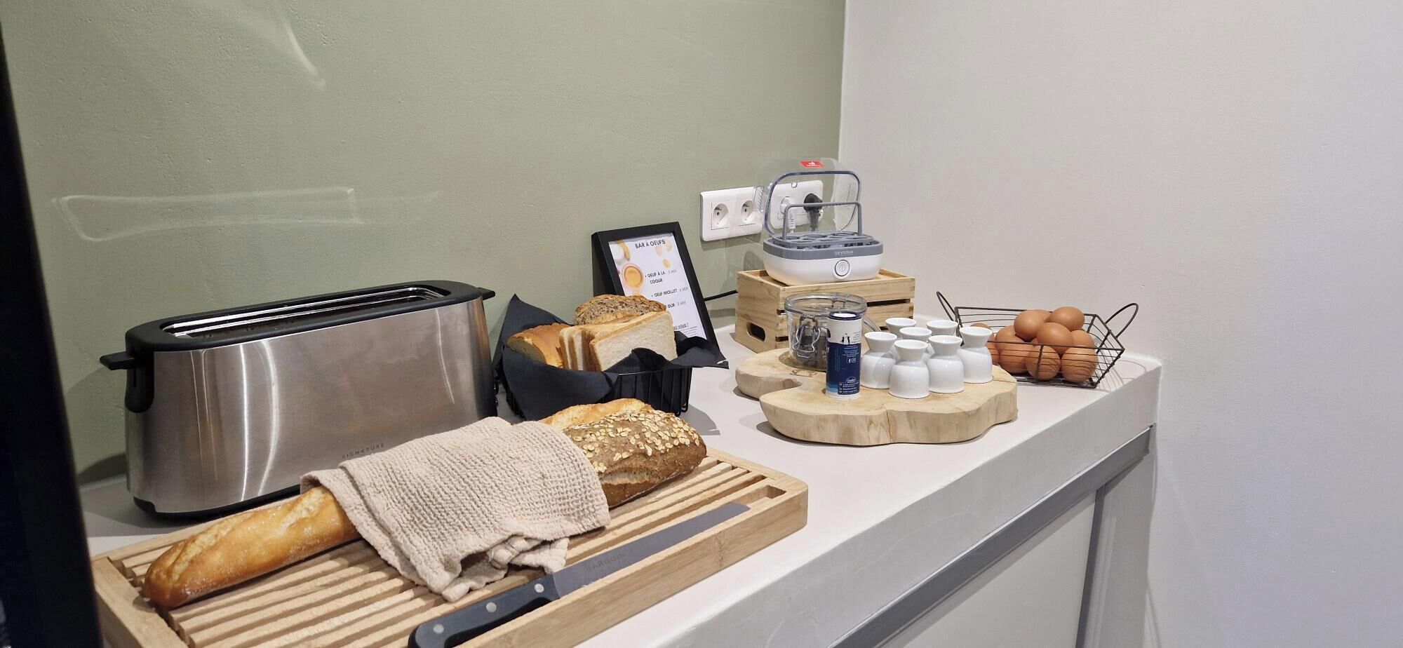 A breakfast buffet setup with a toaster, bread, eggs, and condiments.