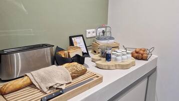 A breakfast buffet setup with a toaster, bread, eggs, and condiments.