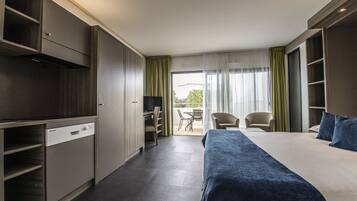 A hotel room with a bed, a desk, a chair, and a balcony with a table and chairs.