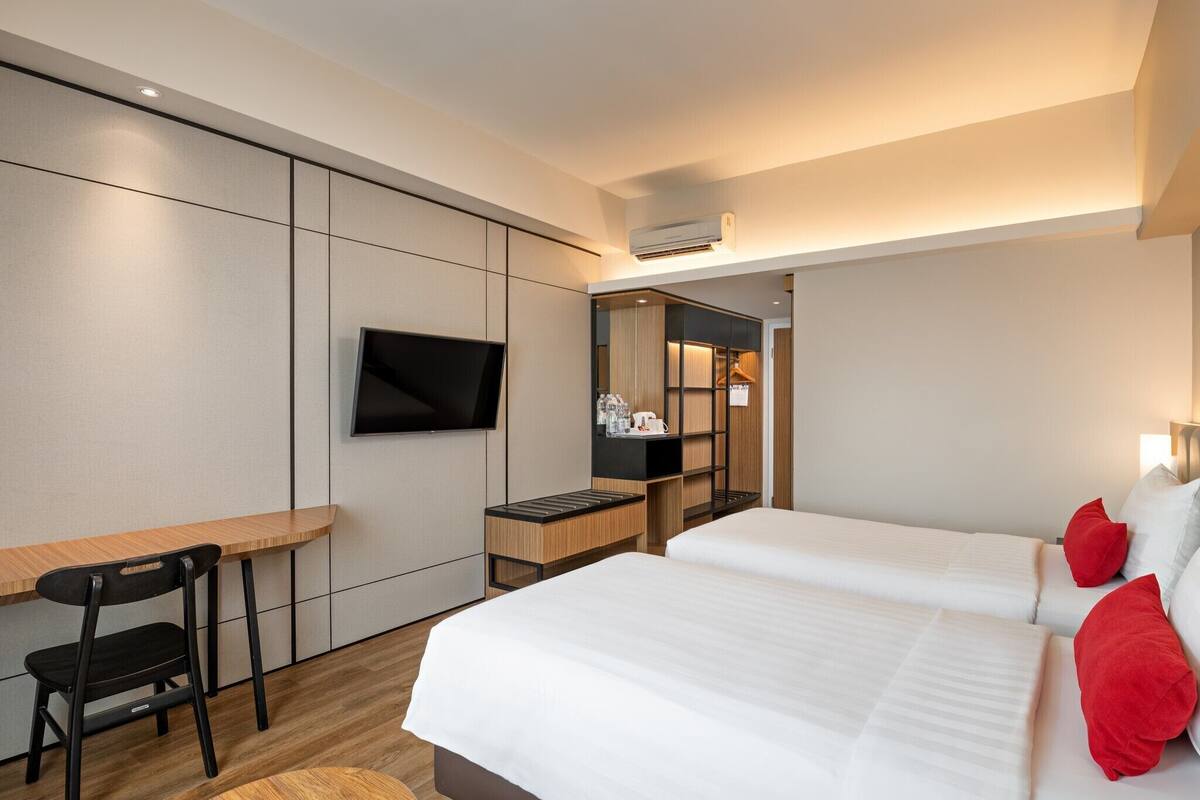 A hotel room with a bed, a desk, a chair, a TV, and a mirror.