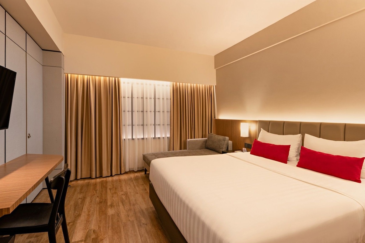 A hotel room with a bed, a desk, a chair, and a TV.