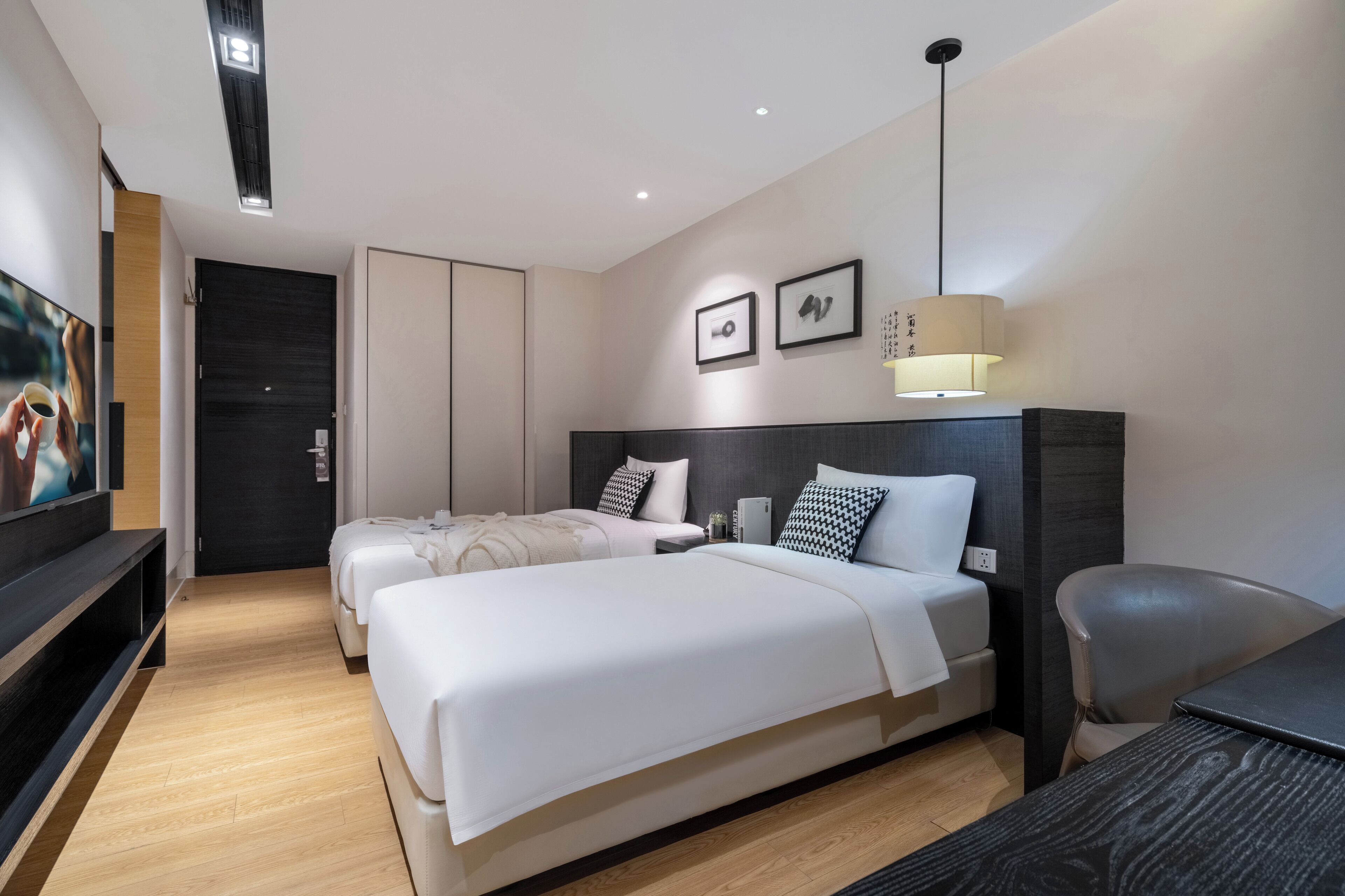 Una habitación de hotel moderna con dos camas, un escritorio, una silla, un televisor y una lámpara.