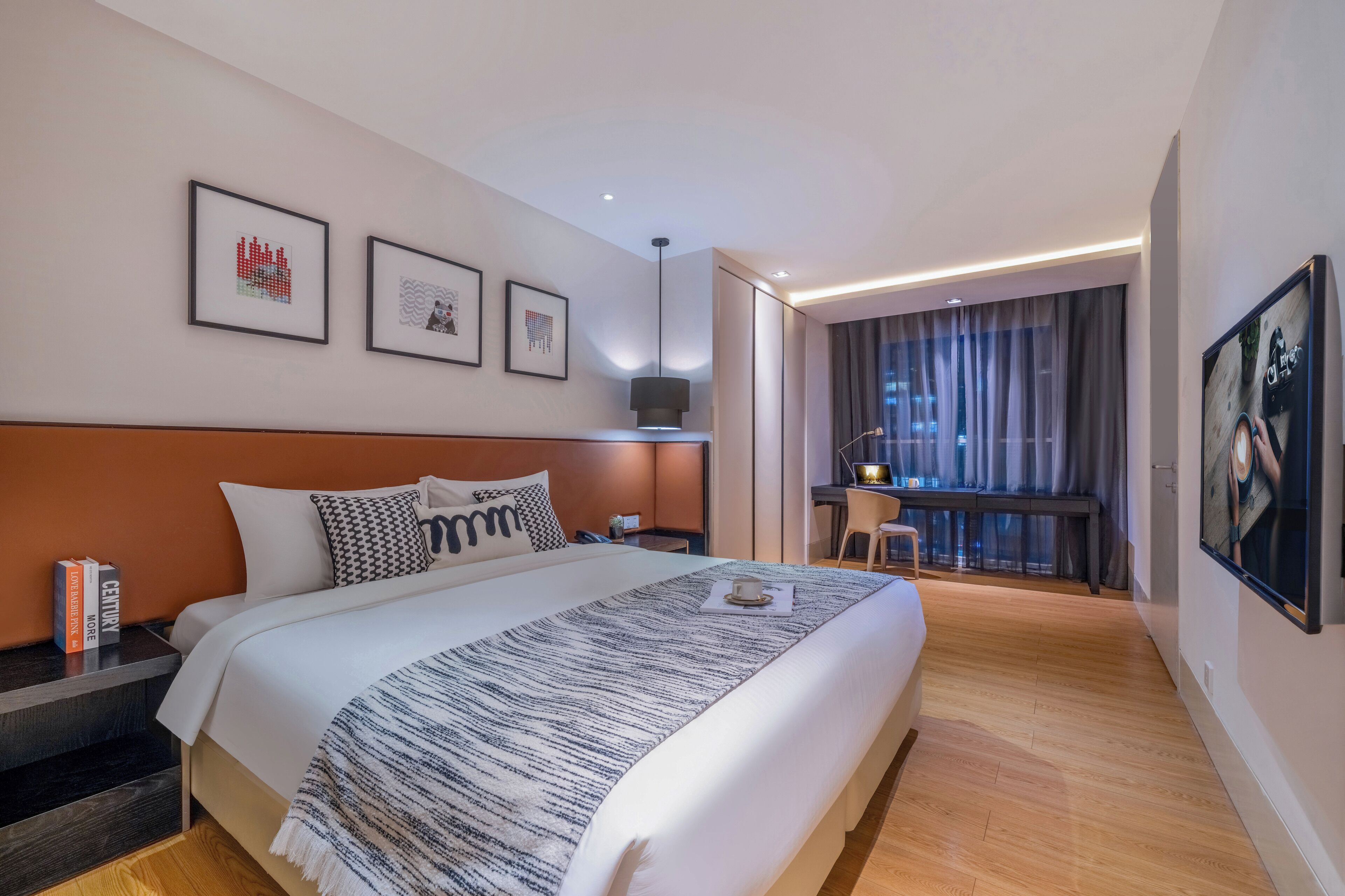 A modern hotel room with a large bed, a desk, and a view of the city.