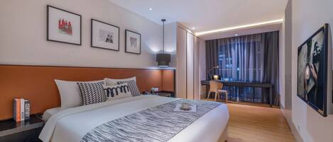 A modern hotel room with a large bed, a desk, and a view of the city.