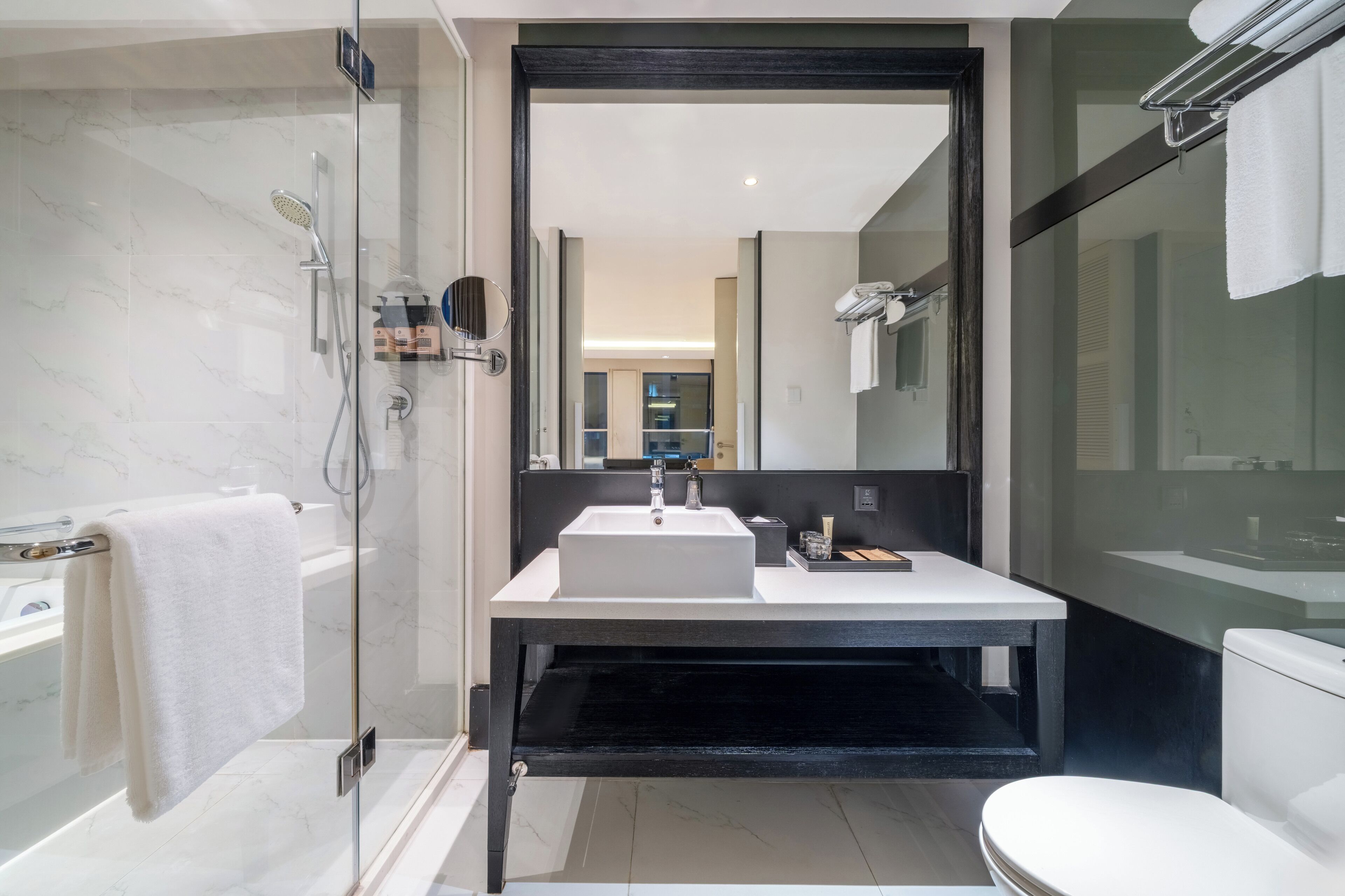 A modern bathroom with a glass-enclosed shower, a white sink, and a black vanity.