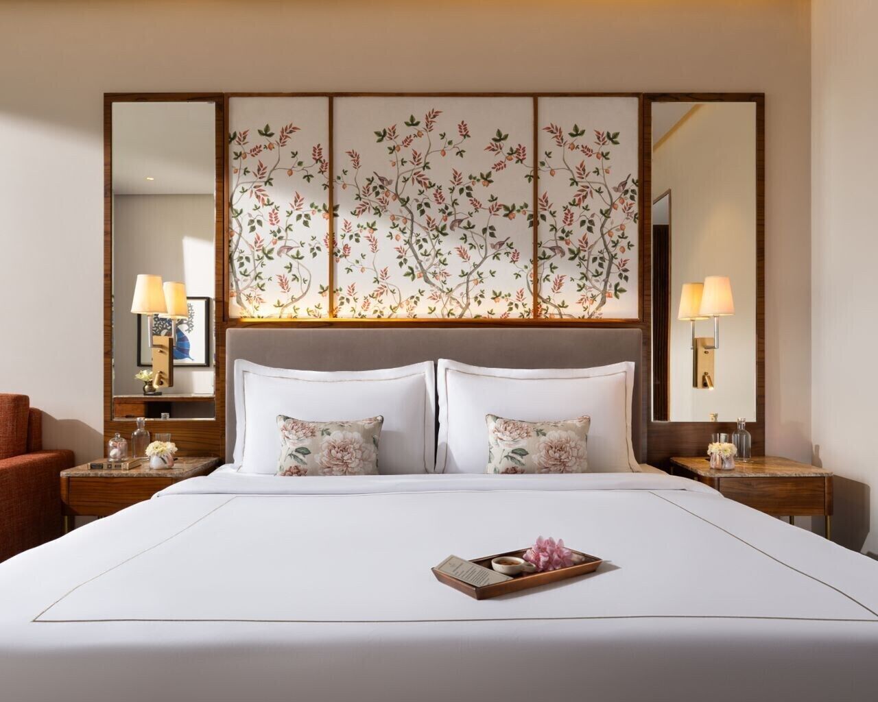 A hotel room with a large bed, two bedside tables with lamps, a large mirror, and a decorative panel above the bed.