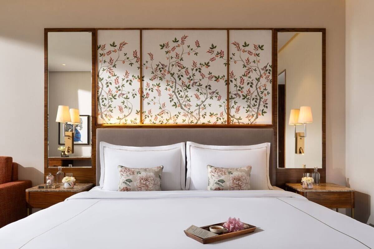 A hotel room with a large bed, two bedside tables with lamps, a large mirror, and a decorative panel above the bed.