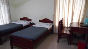 A room with two single beds, a wooden desk, and a chair. - YMCA International House (Kanayannur)