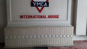 A sign with the YMCA logo and the words "INTERNATIONAL HOUSE" on a wall. - YMCA International House (Kanayannur)