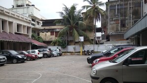 A parking area with multiple cars and a palm tree. - YMCA International House (Kanayannur)