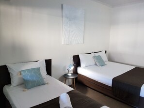 A hotel room with two beds, each with a pillow and a bedside table with a lamp.