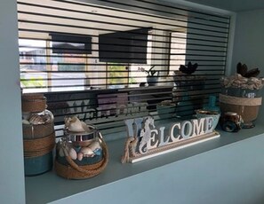 A window display with wicker baskets, a glass jar, and a 'WELCOME' sign.