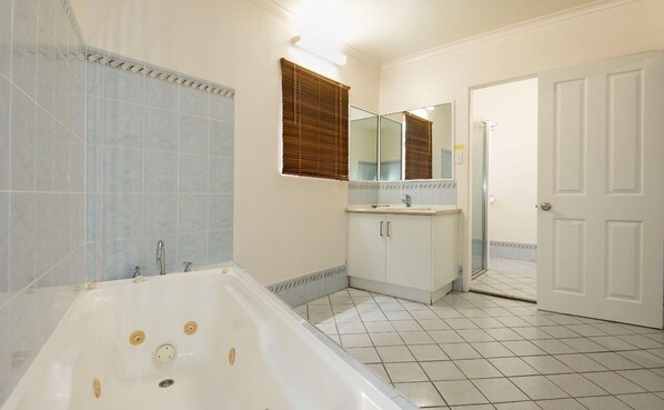 A bathroom with a bathtub, a sink, a mirror, and a door.