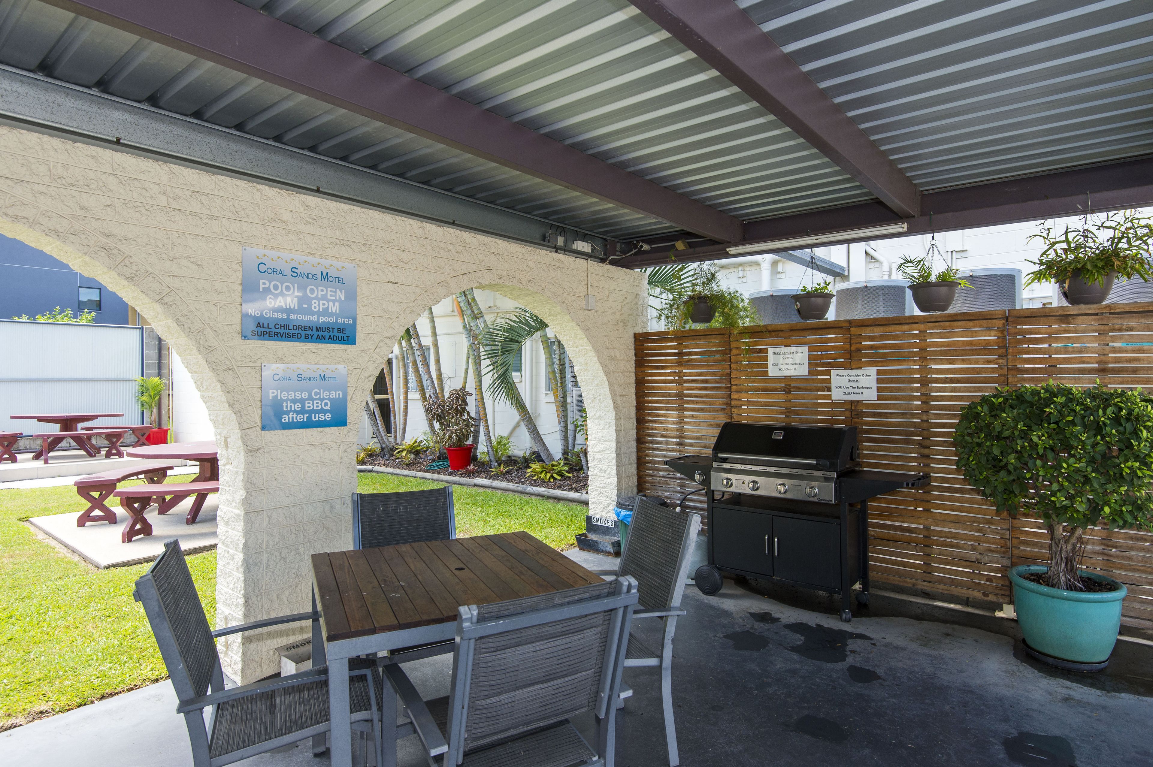 Un espace extérieur aménagé en terrasse, avec un barbecue, des tables de pique-nique et des plantes en pot.