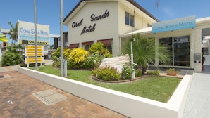The exterior of Coral Sands Motel with a signboard, a landscaped garden, and a paved walkway. - Coral Sands Motel (Mackay)