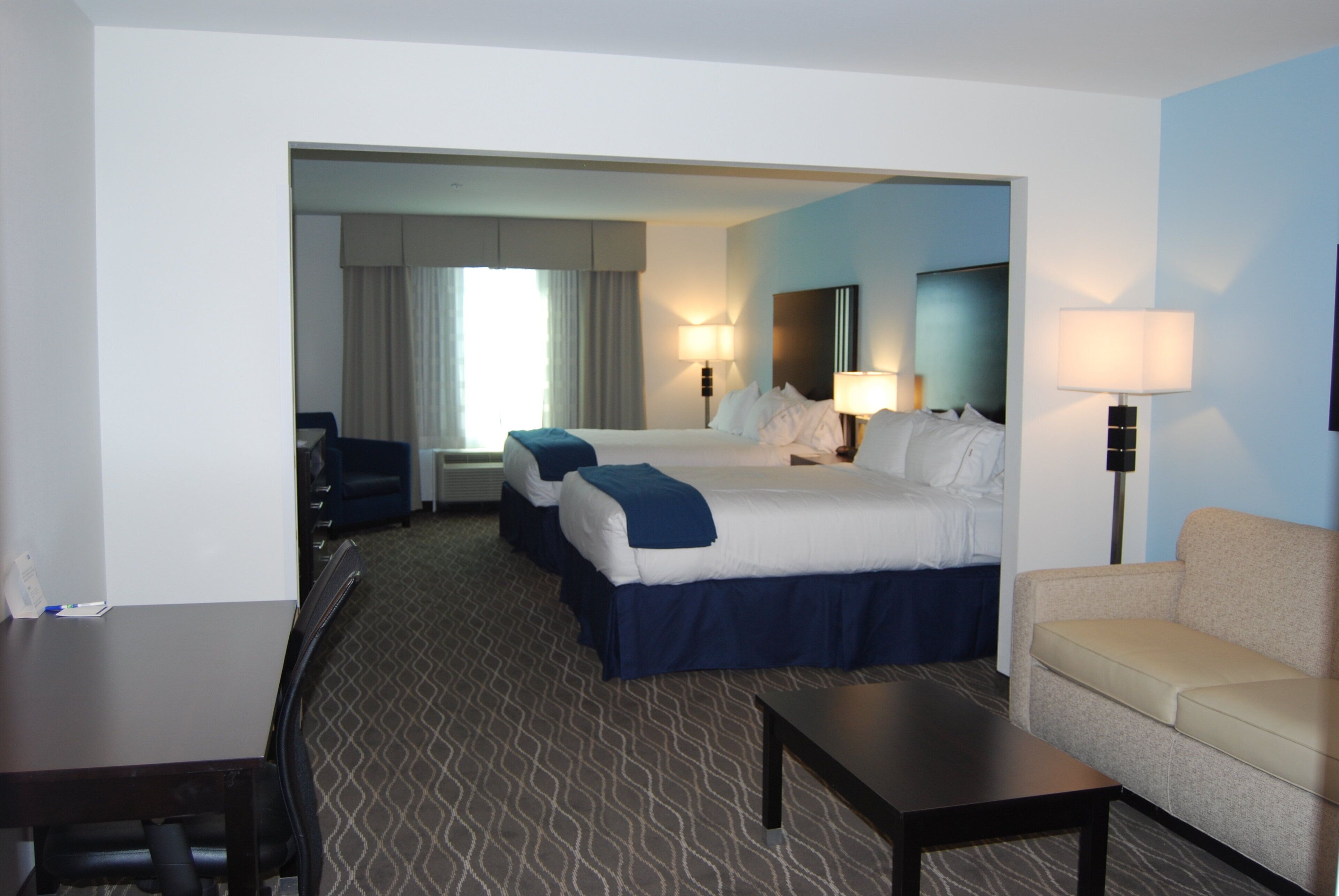 Une chambre d’hôtel avec deux lits, un bureau, une chaise et un canapé.