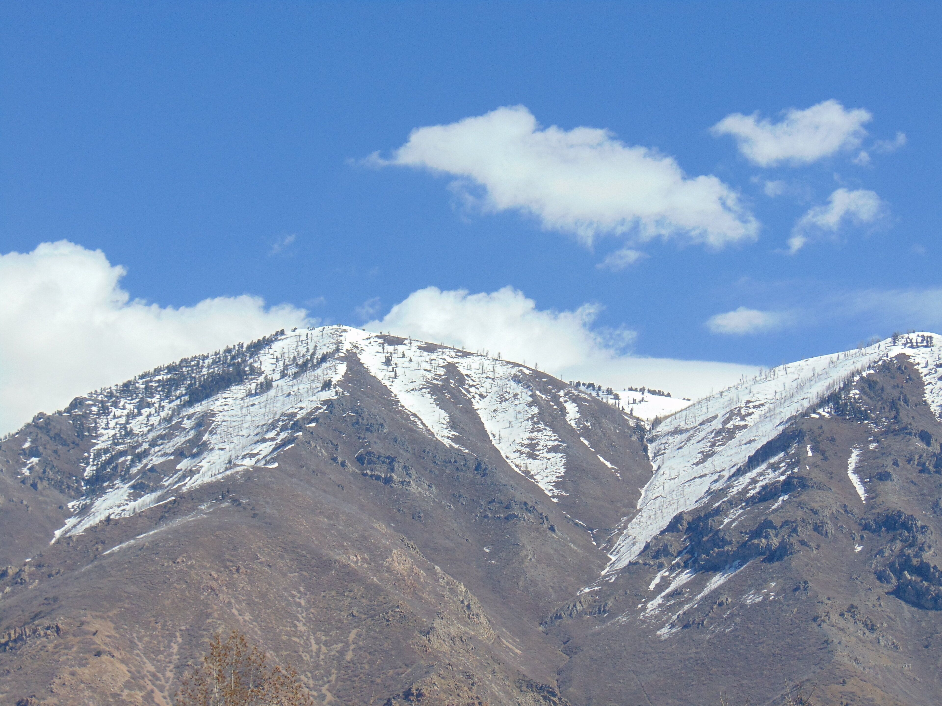 Paisaje montañoso con picos nevados y cielo azul despejado.