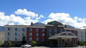Un hotel Holiday Inn Express con un ingresso ben visibile, diversi piani e montagne sullo sfondo.