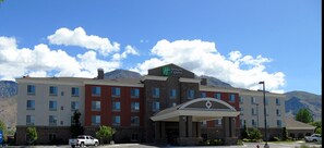 A Holiday Inn Express hotel with a prominent entrance, multiple floors, and a mountainous backdrop. - Holiday Inn Express & Suites Springville-South Provo Area by IHG (Springville)