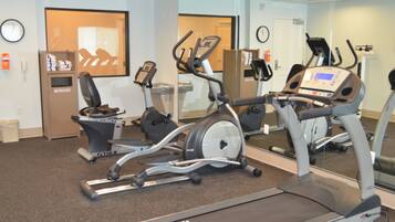 A gym with treadmills, stationary bikes, and a mirrored wall.