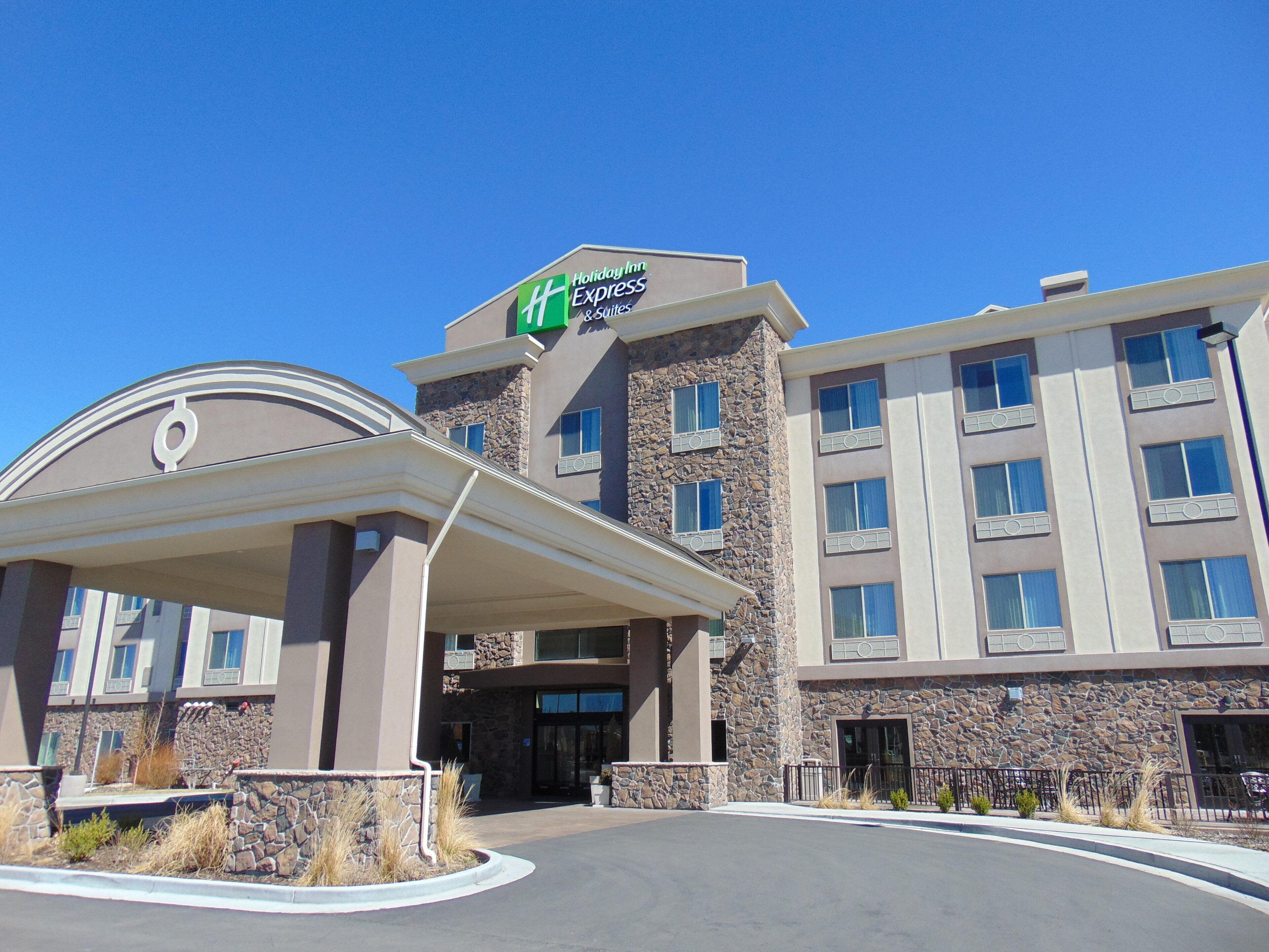 Een Holiday Inn Express hotel met een gevel van natuursteen, een overdekte ingang en een helderblauwe lucht.