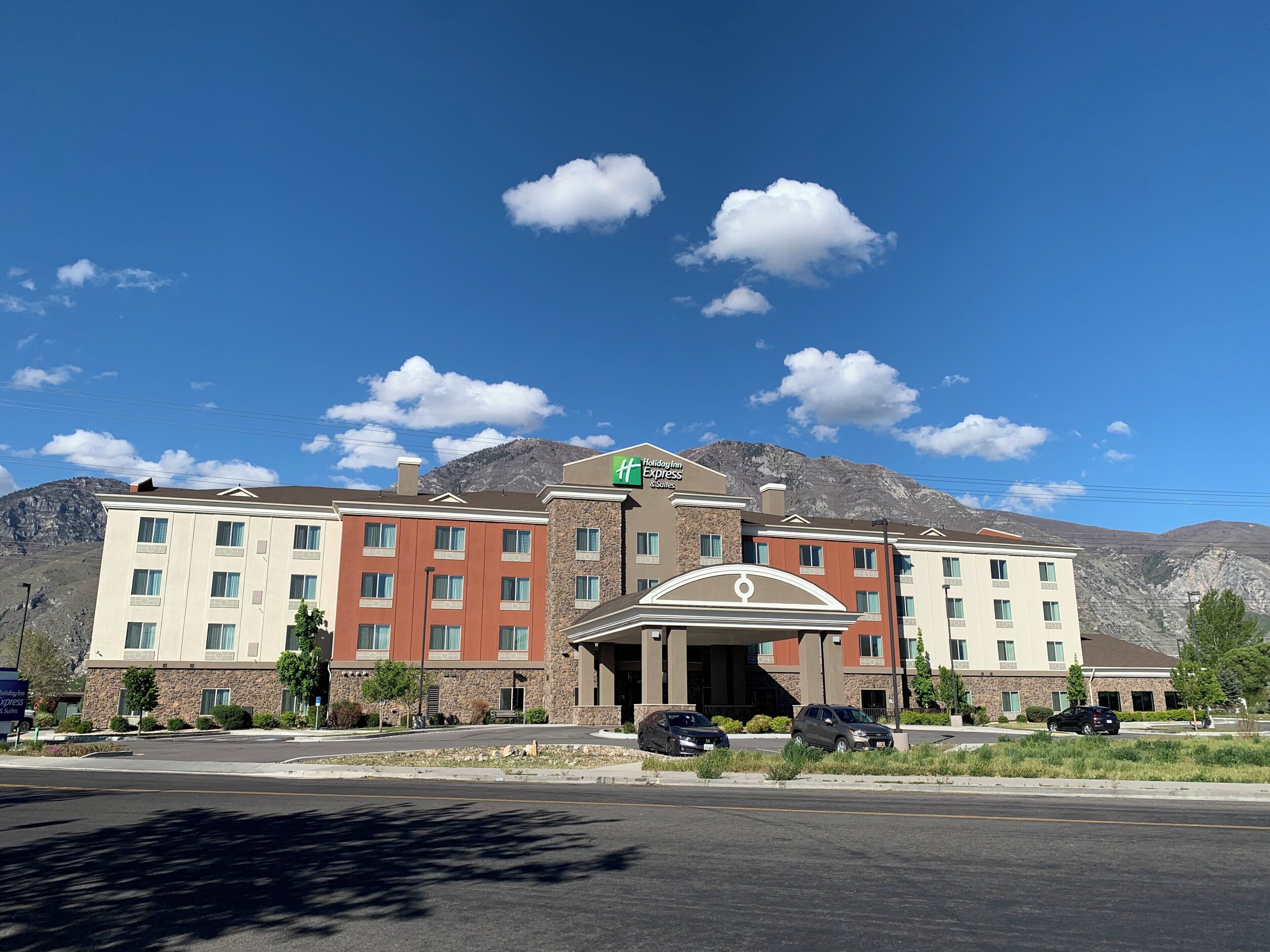 A Holiday Inn Express hotel with a mountain backdrop, featuring a central entrance and multiple floors.