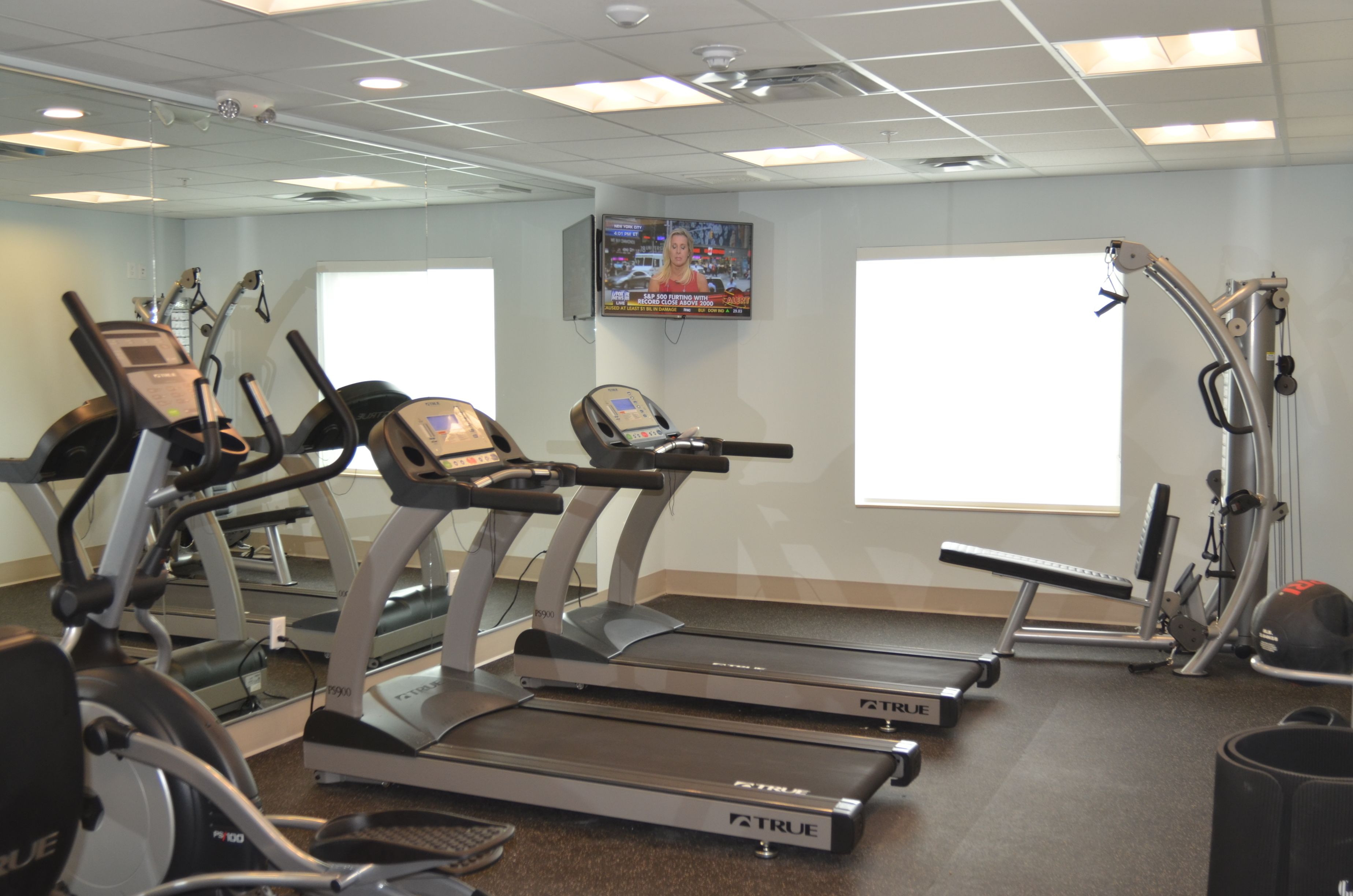 Un gimnasio con cintas de correr, una bicicleta estática y una máquina de pesas.