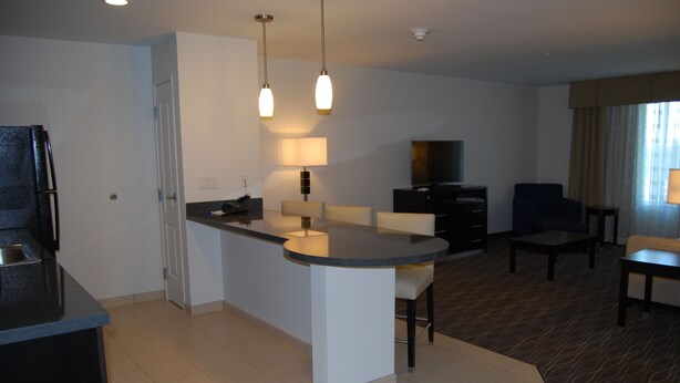 A modern hotel room with a kitchen area, a dining table, a TV, and a seating area. - Holiday Inn Express & Suites Springville-South Provo Area by IHG (Springville)