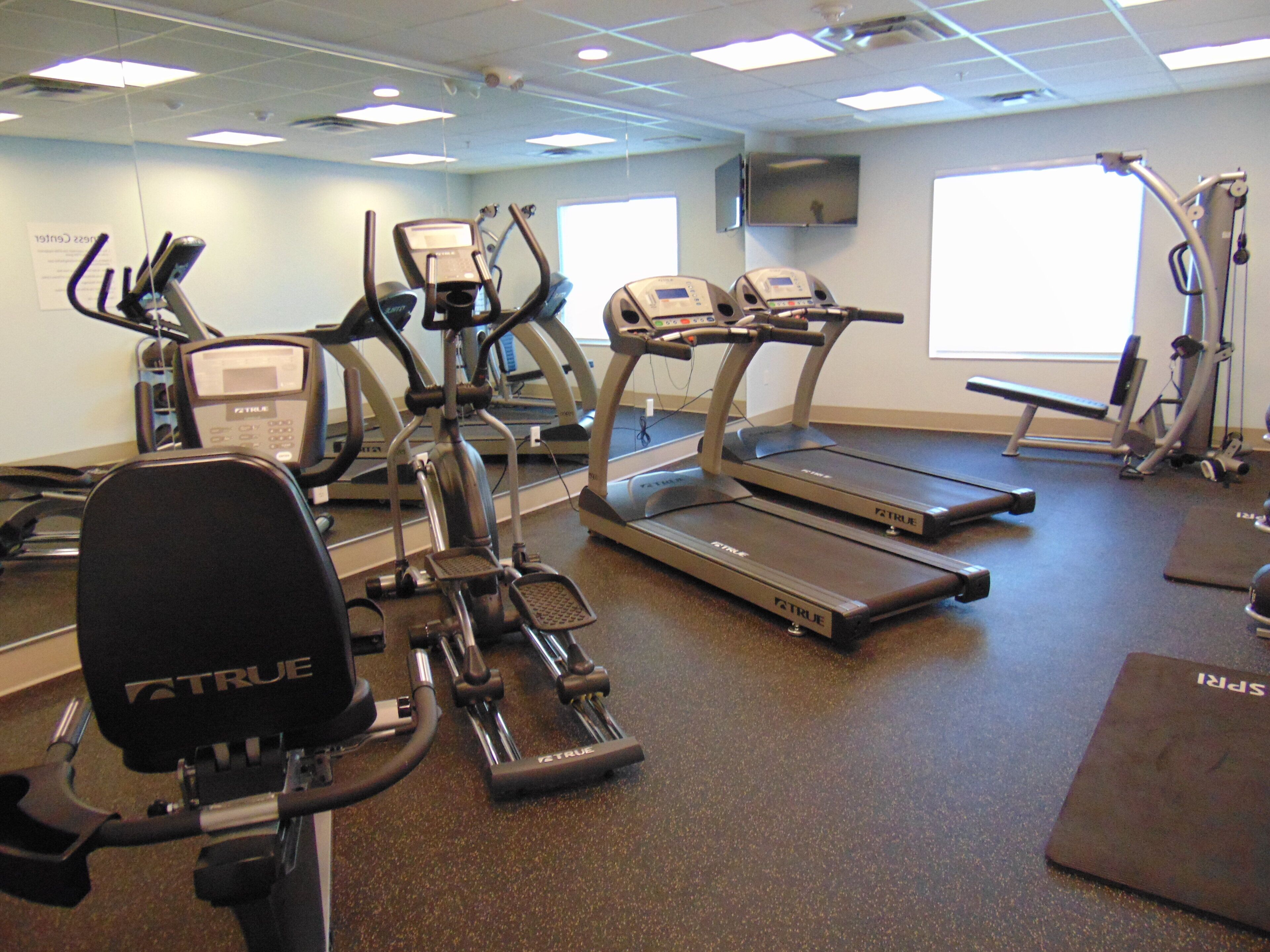 Academia com diversos equipamentos de exercício, incluindo esteiras, elípticos e aparelhos de musculação.