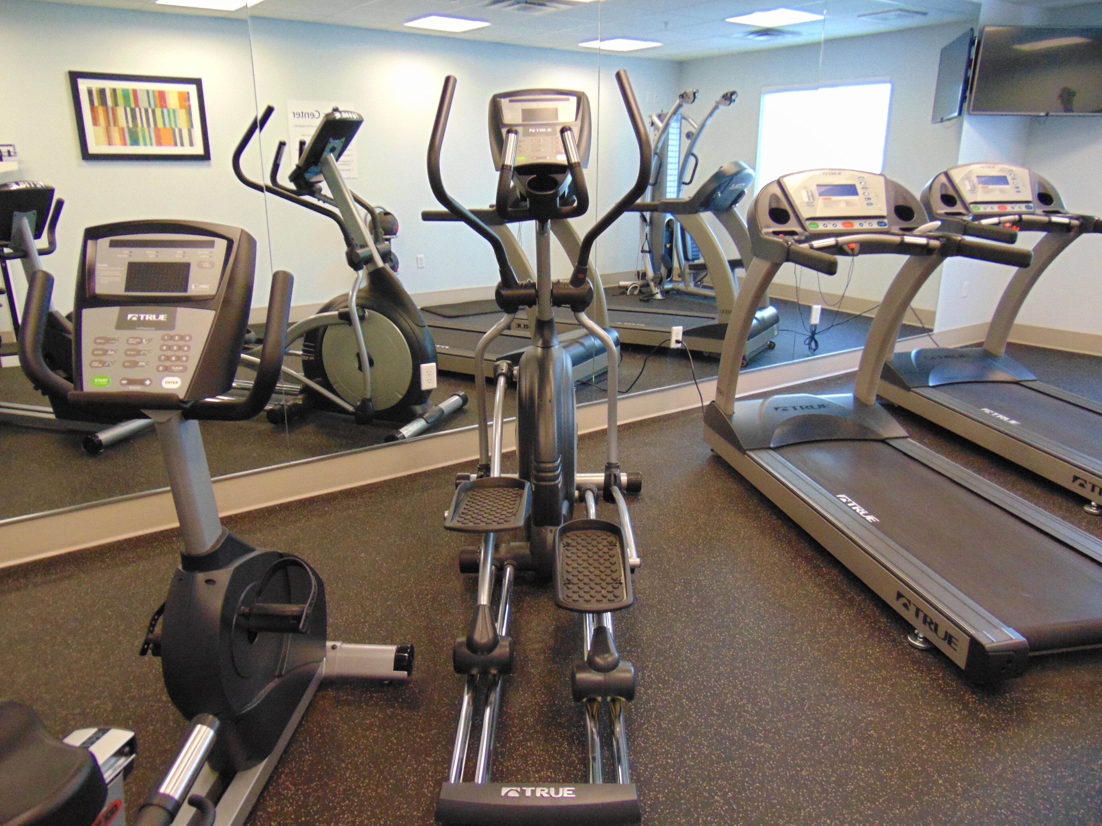 A gym with various exercise equipment including treadmills, stationary bikes, and elliptical machines.
