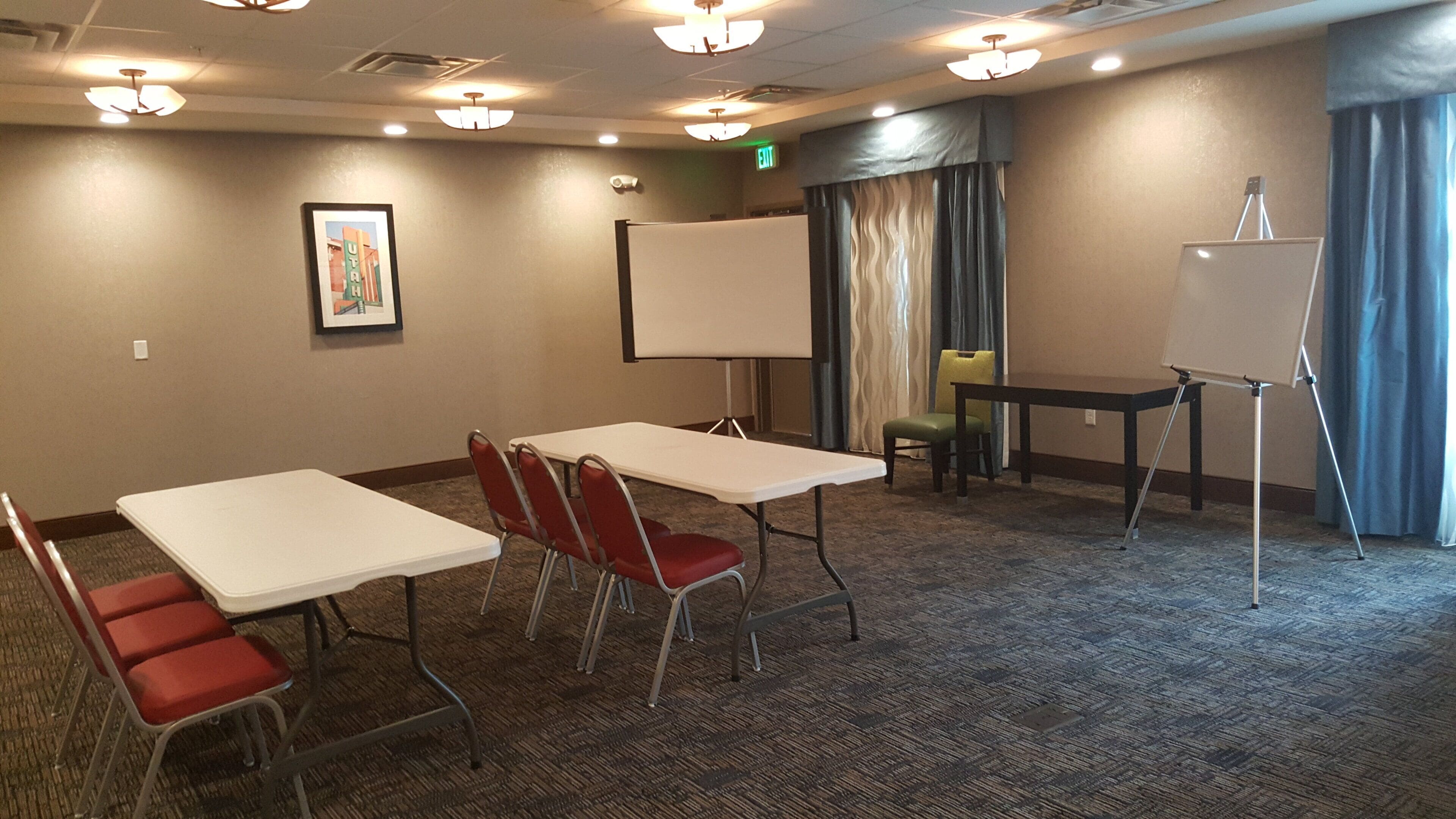 A conference room with tables, chairs, a whiteboard, and a projector.