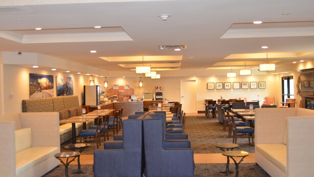 Una hall d'hotel con zone relax, una reception e un'area ristorazione.