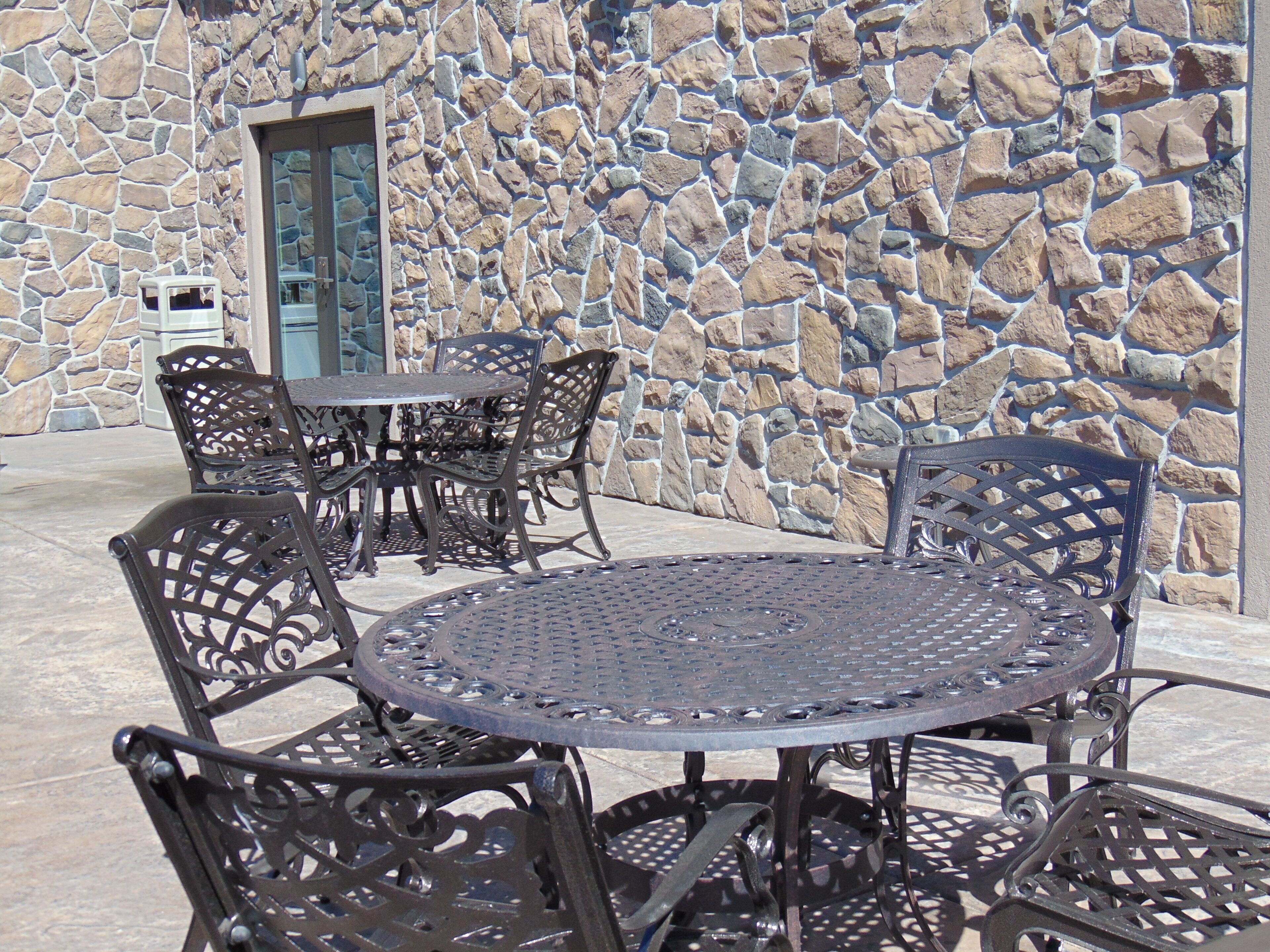 A stone wall with a door and a metal table with chairs.