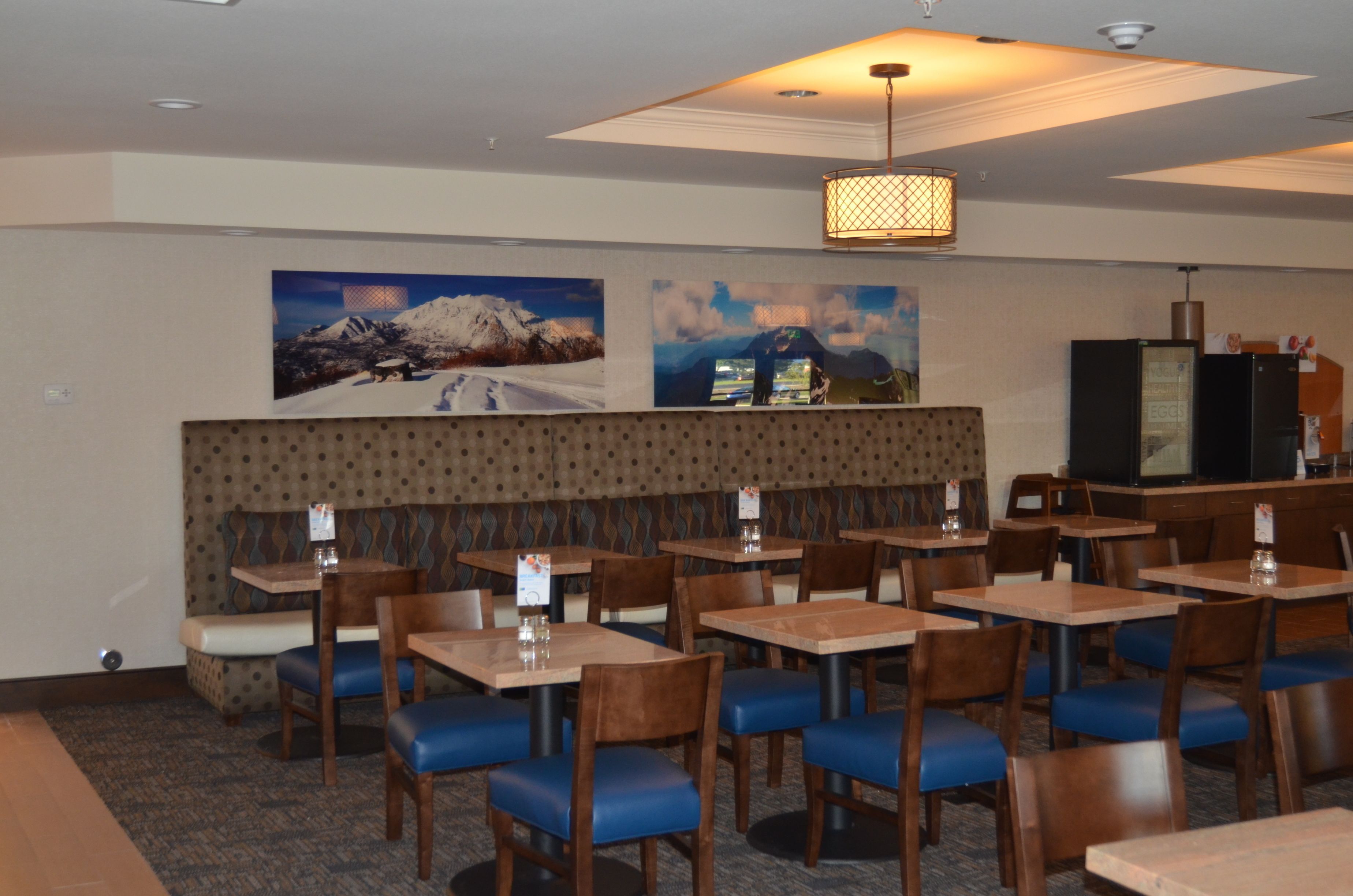 A restaurant with booths and tables, wooden chairs, and a patterned wall.