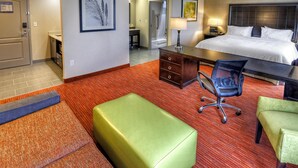 A hotel room with a bed, desk, chairs, and a bathroom visible in the background. - Hampton Inn & Suites Ada (Ada)