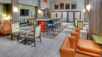 A hotel lobby with seating areas, a bar, and artwork on the walls.