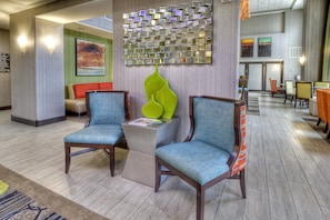 A lobby area with two armchairs, a coffee table, a decorative wall piece, and a seating area with a sofa and chairs. - Hampton Inn & Suites Ada (Ada)
