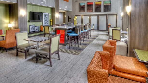 A hotel lobby with a bar area, seating arrangements, and a television mounted on the wall. - Hampton Inn & Suites Ada (Ada)