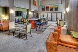 A hotel lobby with a bar area, seating arrangements, and a television mounted on the wall. - Hampton Inn & Suites Ada (Ada)