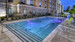 A swimming pool with steps, a stone facade, and a building with multiple windows. - Hampton Inn & Suites Ada (Ada)